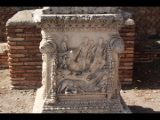 02085 ostia - regio ii - insula vii - sacello dell'ara dei gemelli (ii,vii,3) - altarstein romulus und remus - hier vor ort vorderseite - romulus und remus und die woelfin - hirten - re unten flussgott.jpg